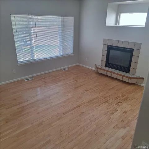 an empty room with wooden floor and fireplace
