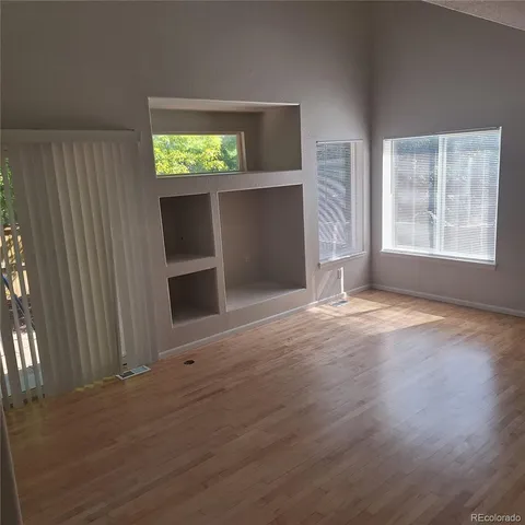 an empty room with wooden floor and windows