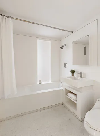 a bathroom with a sink a chair and a refrigerator