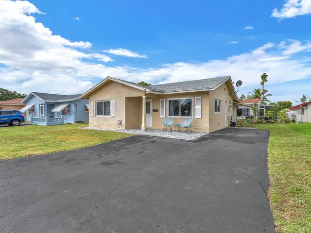a white house with a big yard and large trees