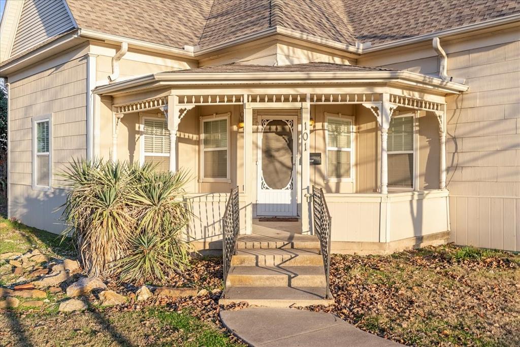 Property entrance featuring roof with shingles and covered porch