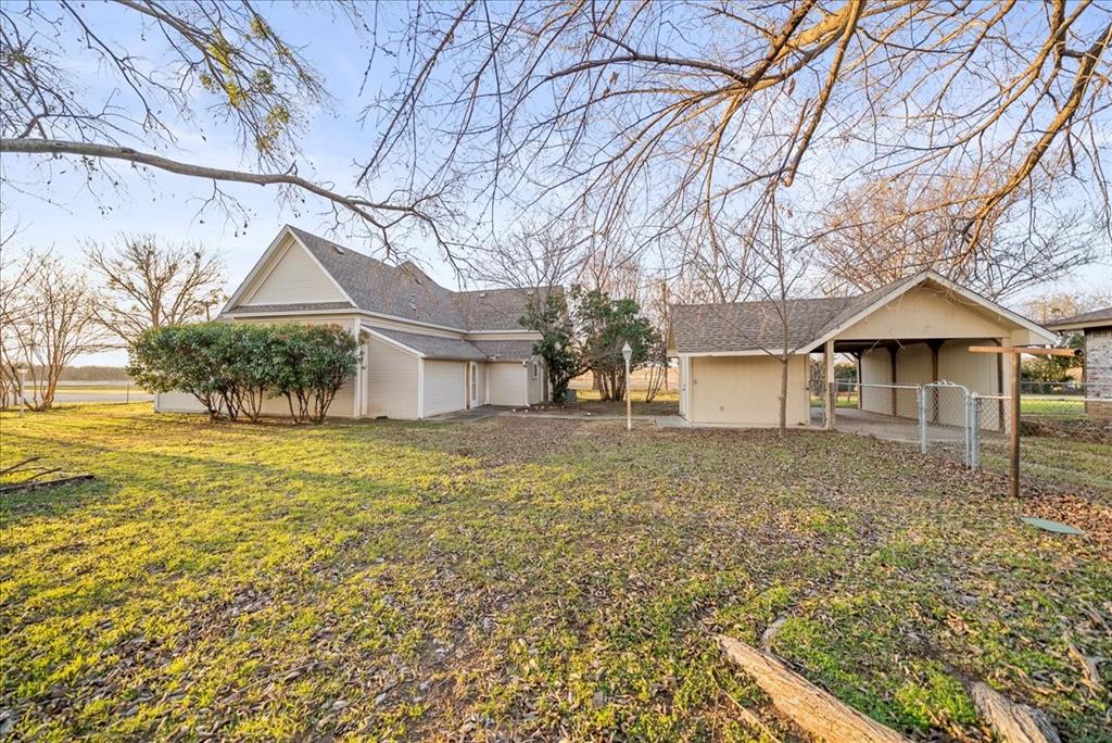 101 North 7th Street Krum, TX 76249 - Photo 22 of 26 View of yard featuring an attached garage, a carport, and a patio area