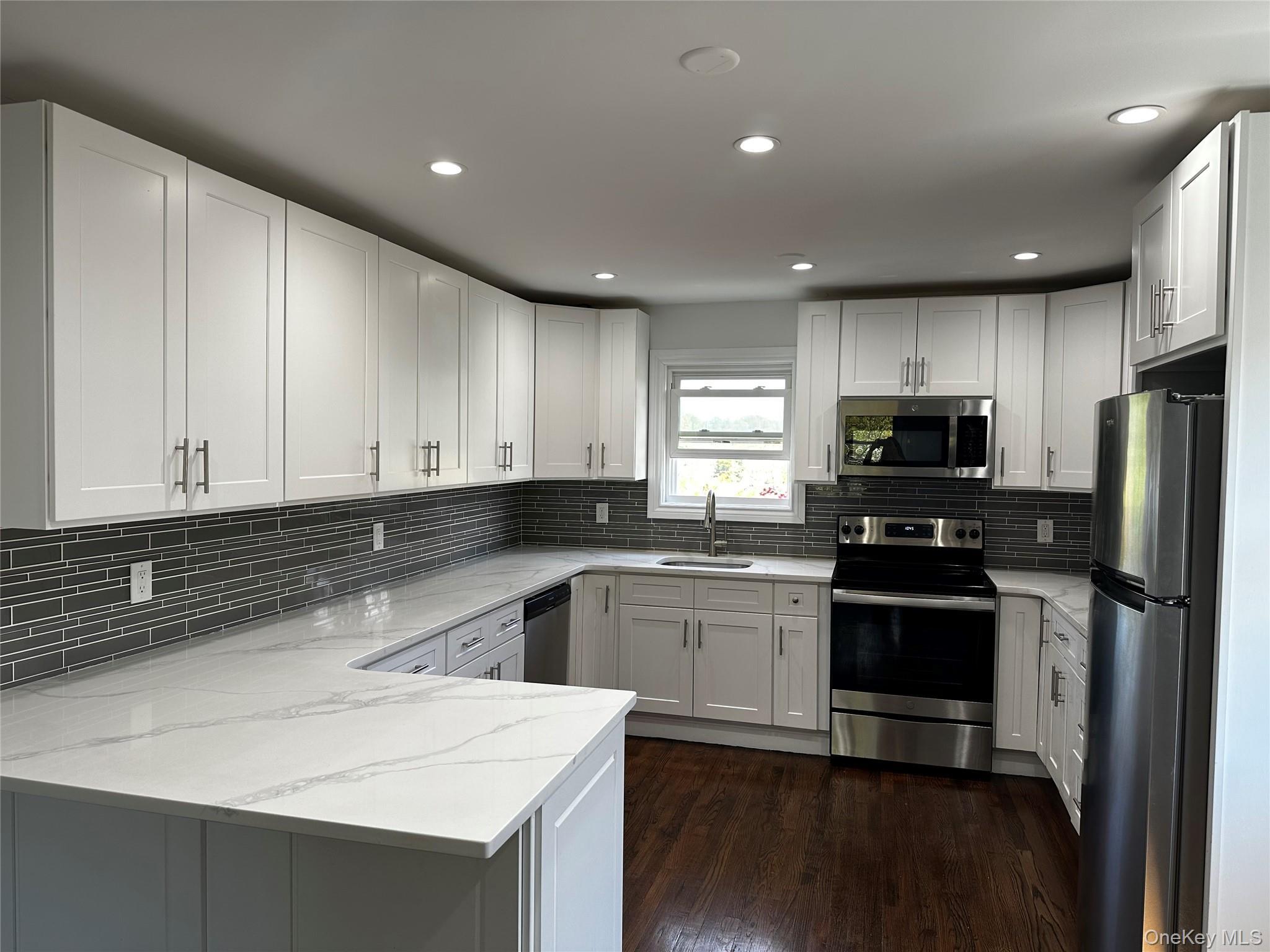 56 Marwood Road North, Unit 2 Port Washington, NY 11050 - Photo 2 of 11 a kitchen with a sink a stove a refrigerator and cabinets