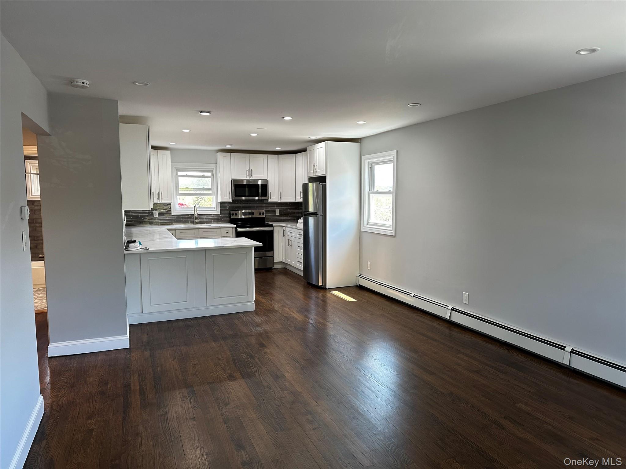 56 Marwood Road North, Unit 2 Port Washington, NY 11050 - Photo 3 of 11 a kitchen with stainless steel appliances a refrigerator and wooden floor