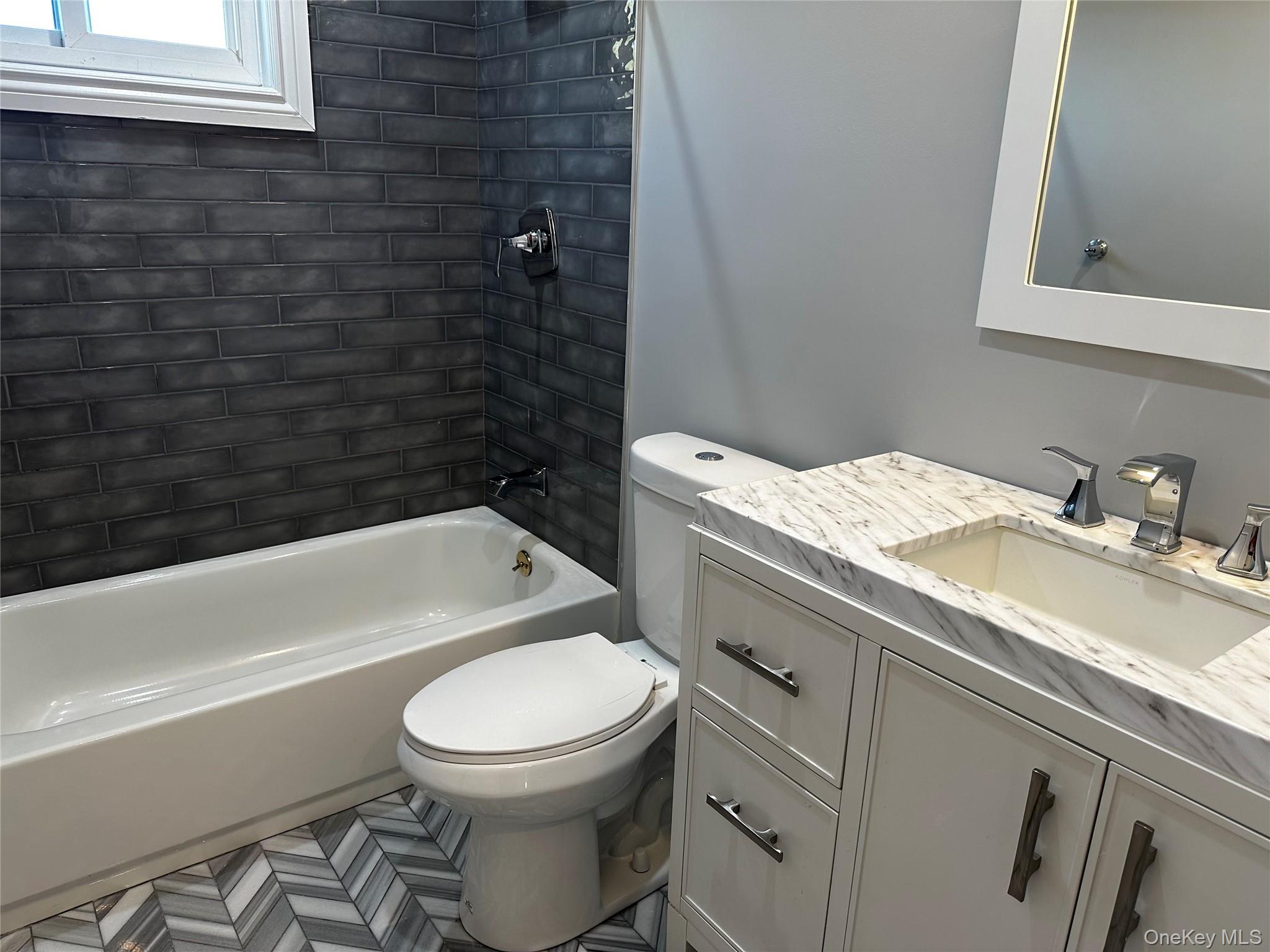 56 Marwood Road North, Unit 2 Port Washington, NY 11050 - Photo 9 of 11 a bathroom with a granite countertop toilet sink and mirror