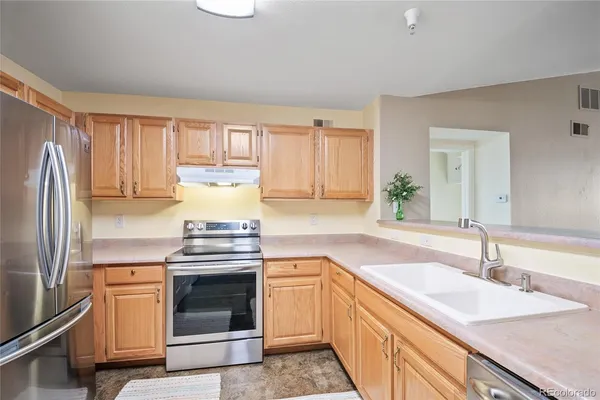 a kitchen with granite countertop a sink stove and refrigerator