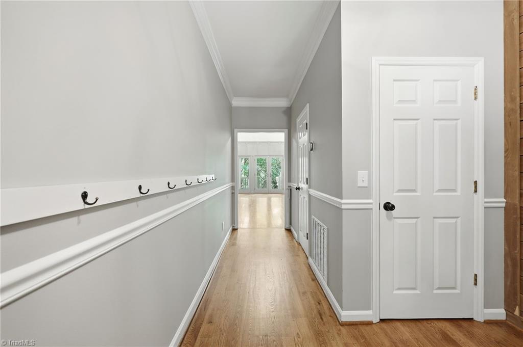8861 Boylston Road Colfax, NC 27235 - Photo 8 of 50 Thoughtfully designed main hallway featuring hardwood floors, elegant trim details, and convenient coat hooks, leading toward the home's open living spaces.