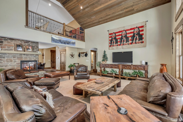 9049 Timphaven Road Sundance, UT 84604 - Photo 14 of 63 Living area with arched walkways, a vaulted wooden ceiling, a stone fireplace, and carpet floors