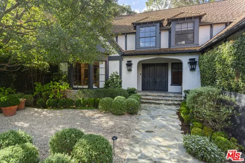 a view of a brick house with a yard and plants