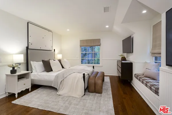 a spacious bedroom with a bed and a flat screen television