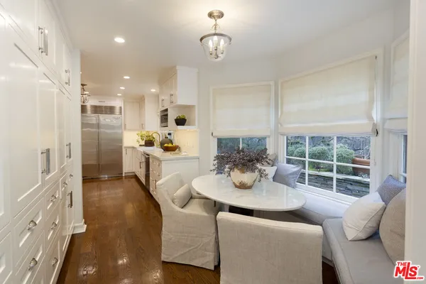 a kitchen with stainless steel appliances kitchen island granite countertop a refrigerator a sink a dining table and chairs