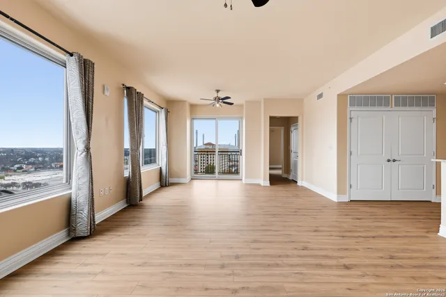 a view of a big room with wooden floor and windows