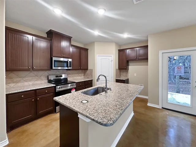 a kitchen with cabinets and center island with wooden floor