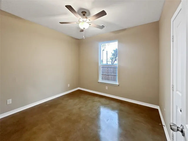 an empty room with windows and ceiling fan