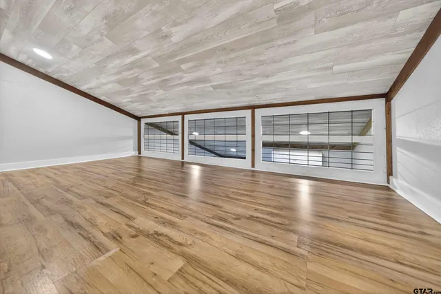 a view of an empty room with wooden floor and fan