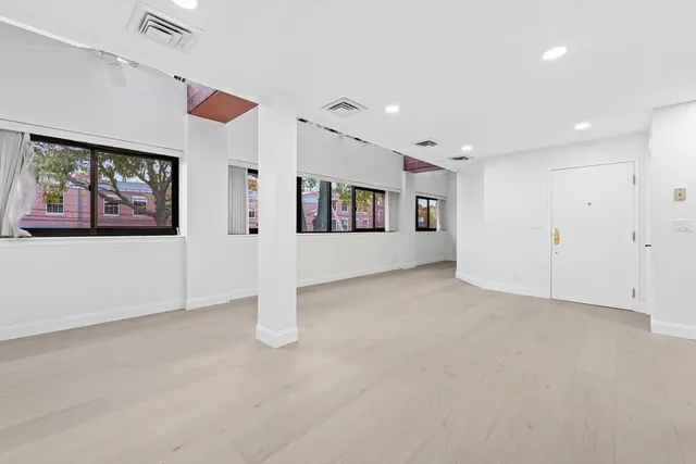 an empty room with windows and ceiling fan