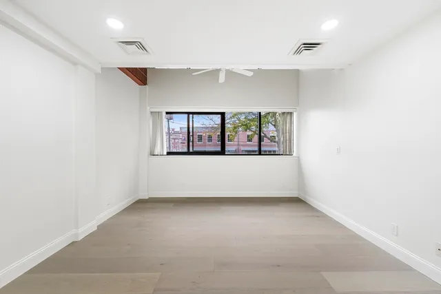 a large white bed sitting in a bedroom next to a window with a potted plant on a dresser