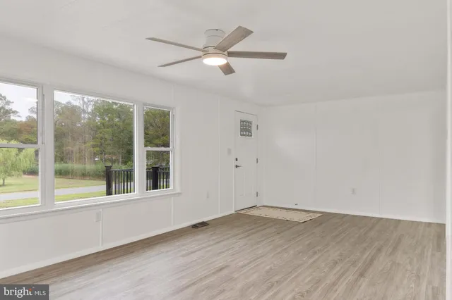 an empty room with wooden floor and a ceiling fan