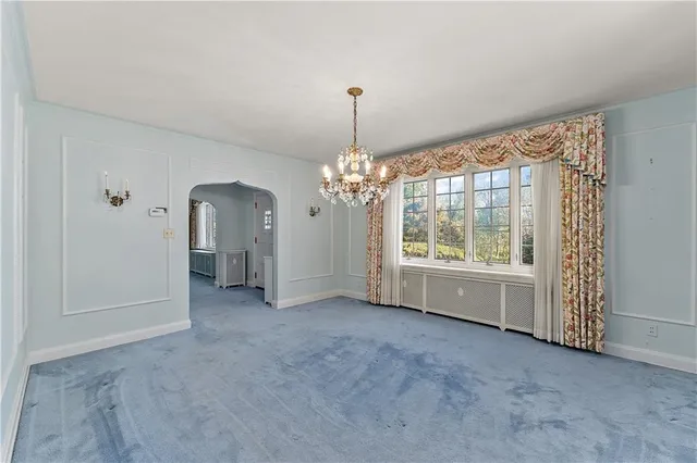 an empty room with windows and chandelier