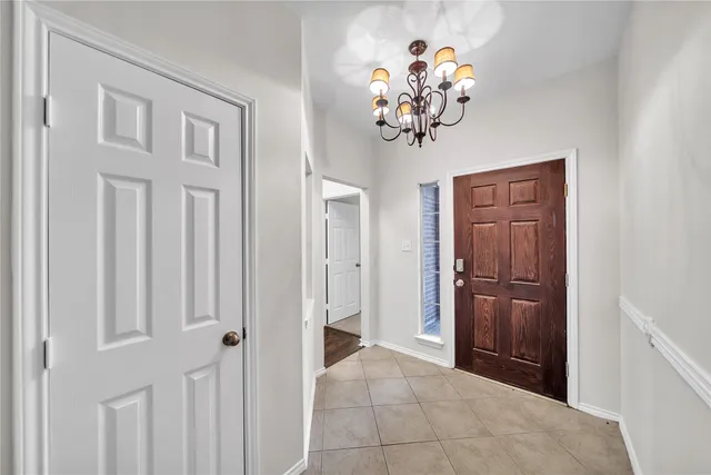 an empty room with windows and chandelier fan