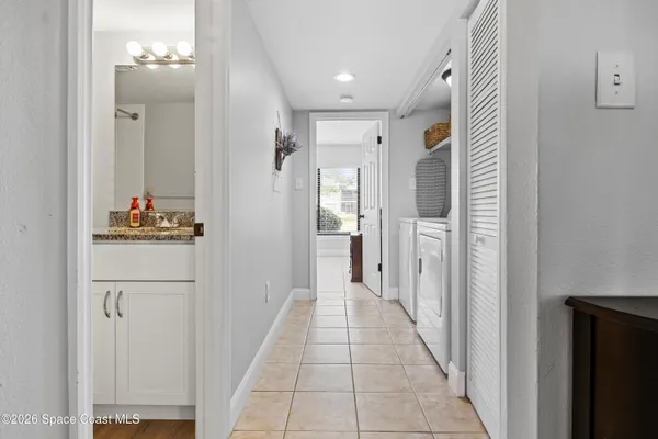 a hallway with white cabinets and chandelier