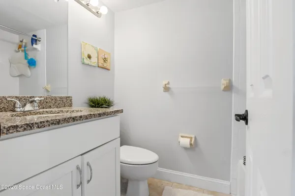 a bathroom with a granite countertop sink and a toilet