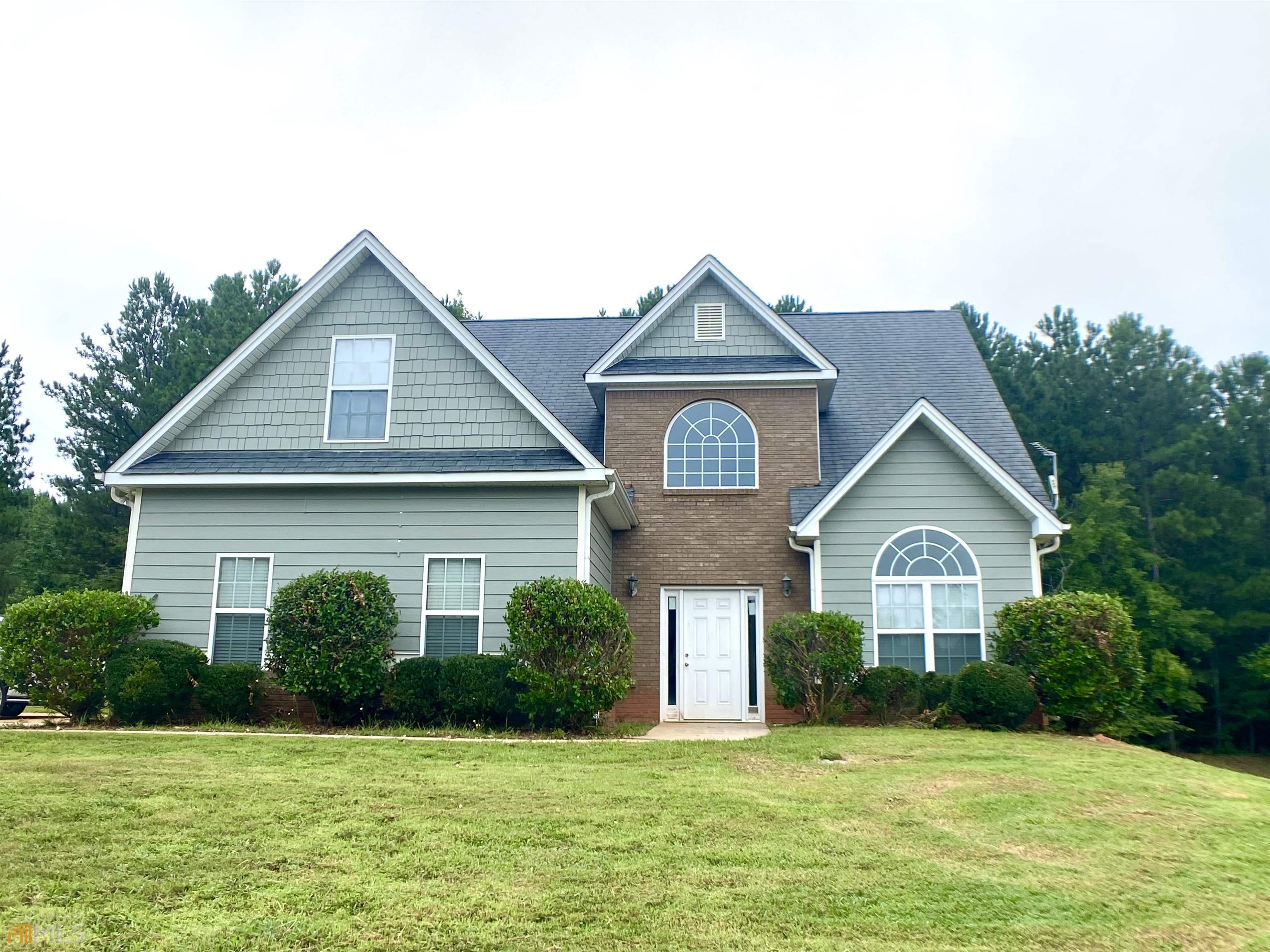 a front view of a house with a yard and trees