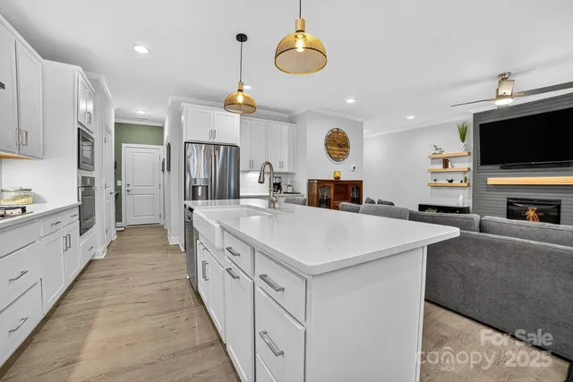 a kitchen with stainless steel appliances granite countertop a sink a stove a refrigerator and a dining table with wooden floor