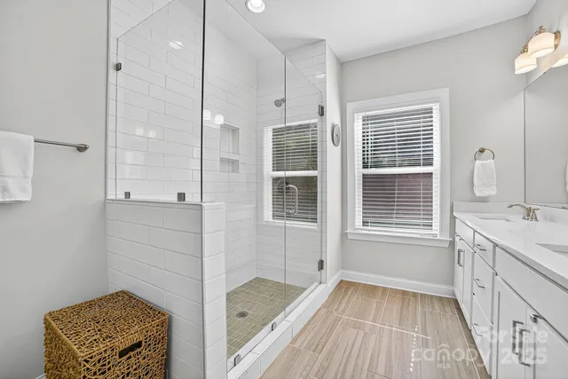 a spacious bathroom with a double vanity sink a mirror and a shower