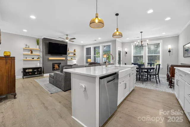 a large white kitchen with a sink and dishwasher a stove top oven with wooden floor