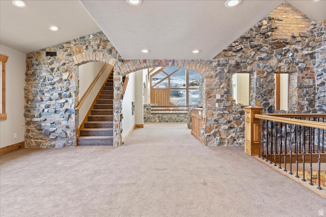 246 Woods Creek Road Morgan, UT 84050 - Photo 37 of 69 Stone and brick accent walls, arched doorways, recessed lighting, carpeted flooring, and a staircase with wood railing and metal balusters