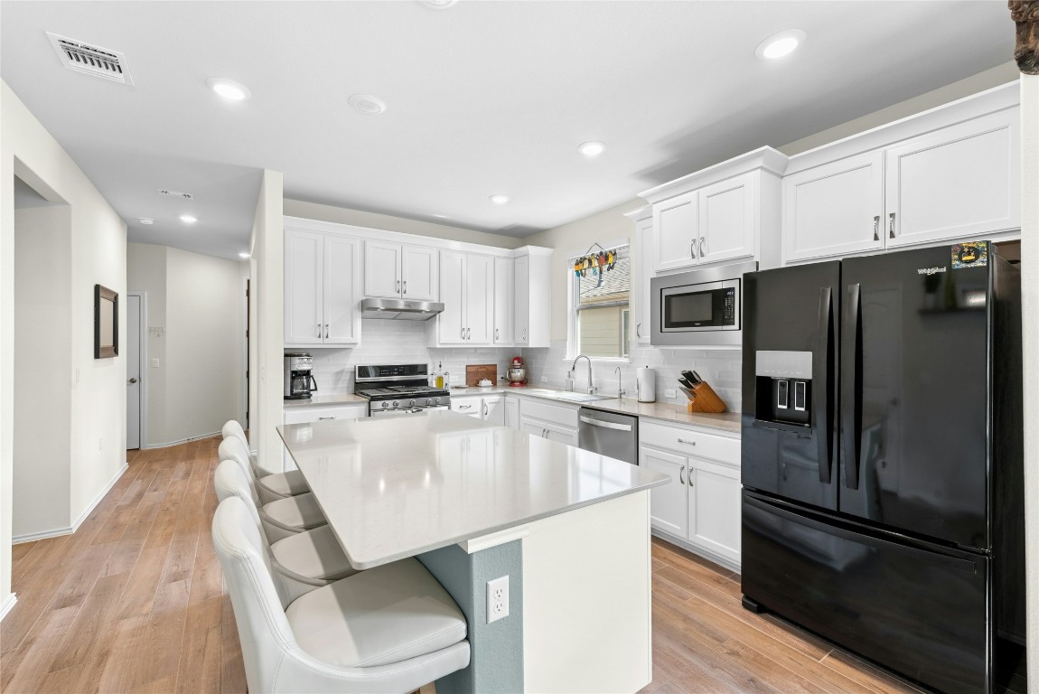 104 Coachsmith Street Georgetown, TX 78633 - Photo 10 of 38 a kitchen with kitchen island a refrigerator stove microwave and cabinets