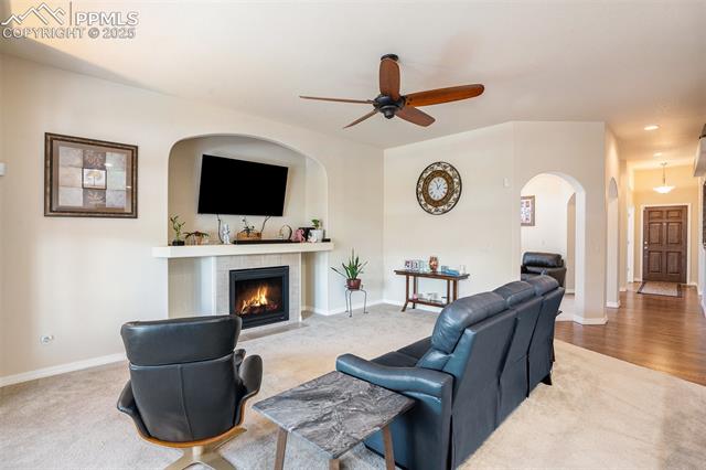 9709 Rockingham Drive Peyton, CO 80831 - Photo 7 of 50 Carpeted living room with a ceiling fan, a tiled fireplace, arched walkways, and recessed lighting