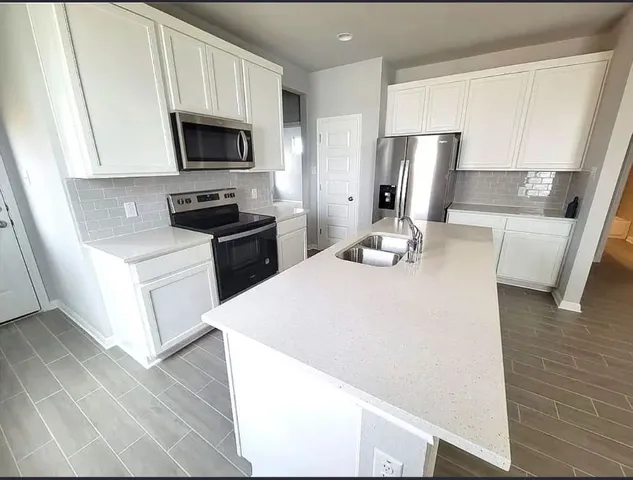 a kitchen with a sink a microwave a refrigerator and wooden floor