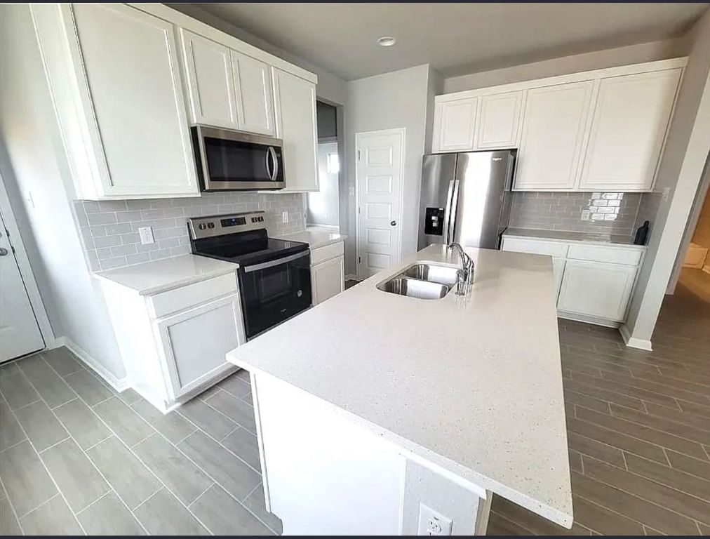 489 Unforgiven Lane Jarrell, TX 76537 - Photo 3 of 9 a kitchen with a sink a microwave a refrigerator and wooden floor