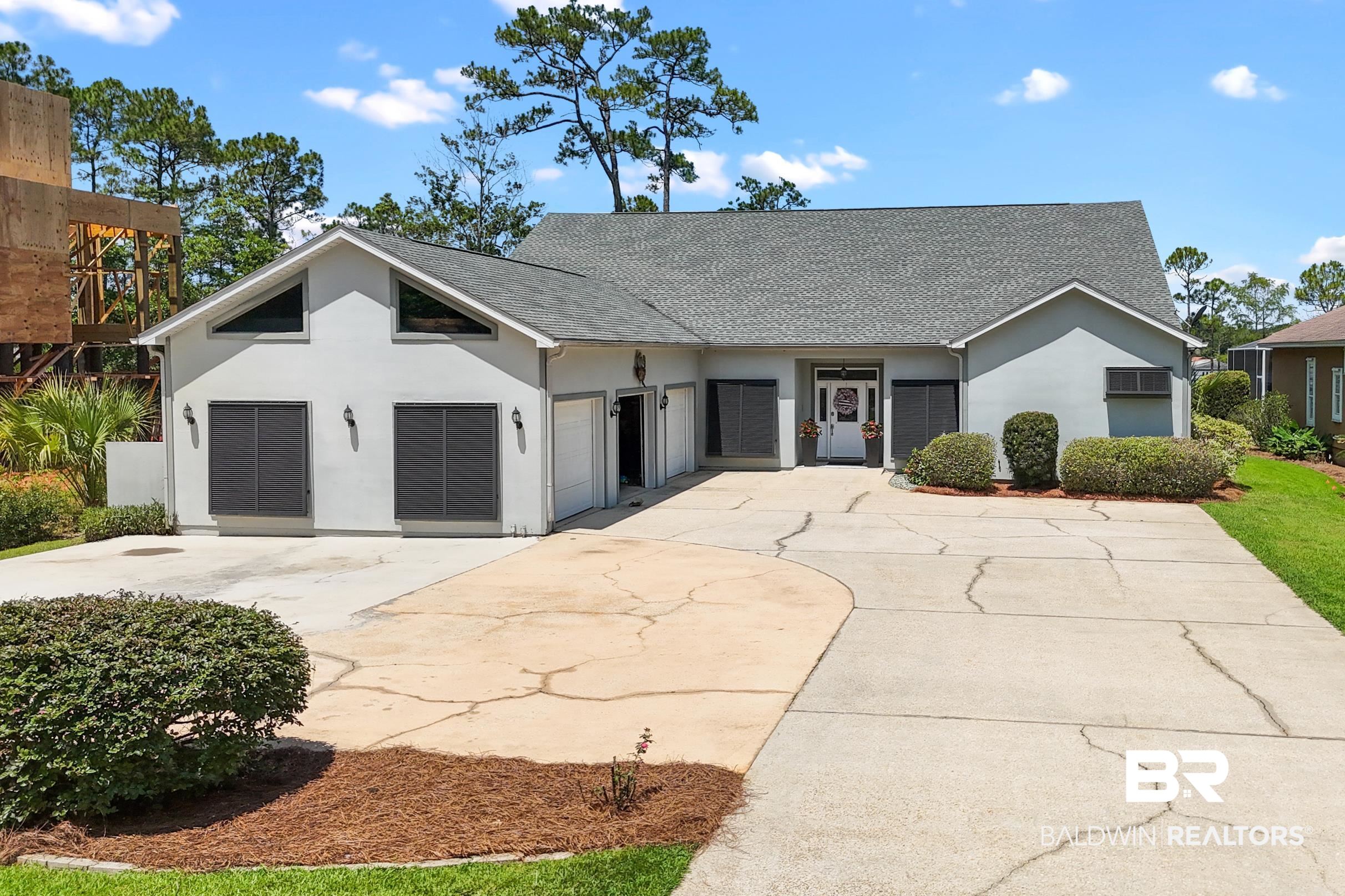 View of front facade featuring stucco siding, concrete driveway, a shingled roof, and an AC wall unit