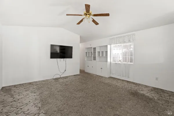 a living room with a flat screen tv and a ceiling fan
