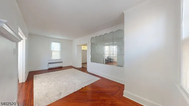 a view of an empty room with window and wooden floor