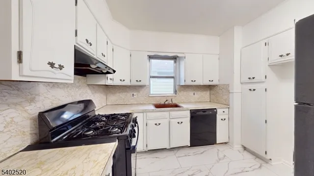 a kitchen with stainless steel appliances a stove a sink and white cabinets