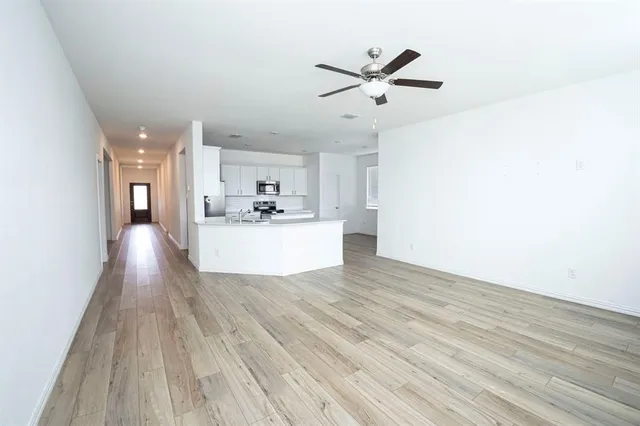 a view of a living room with wooden floor and white walls
