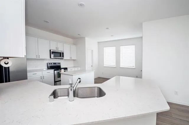 a kitchen with stainless steel appliances a sink a microwave a refrigerator and cabinets
