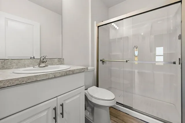 a bathroom with a granite countertop sink a toilet and shower