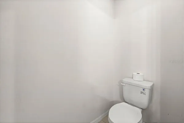 a white toilet sitting next to a white wall