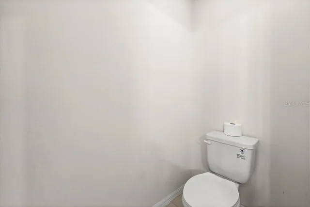 a white toilet sitting next to a white wall