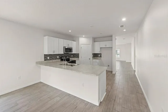 a kitchen with stainless steel appliances granite countertop a sink a stove a refrigerator and cabinets