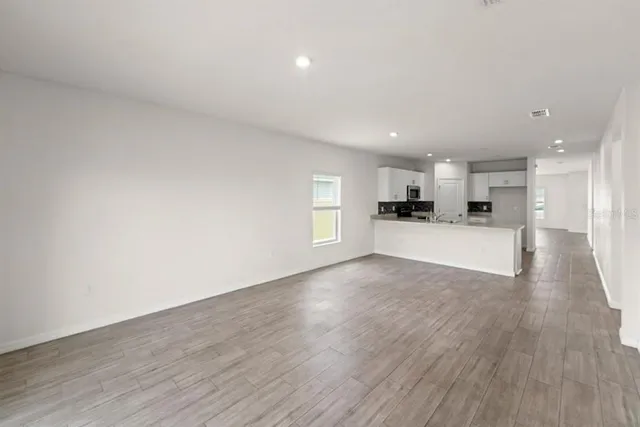a view of a kitchen with a fridge and wooden floor
