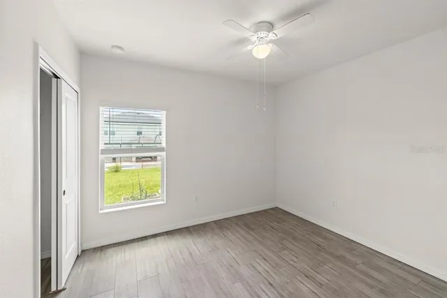 an empty room with a window and a ceiling fan