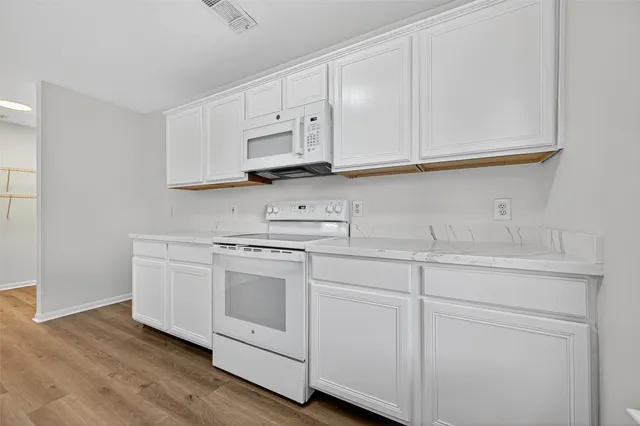 a kitchen with white cabinets and white appliances