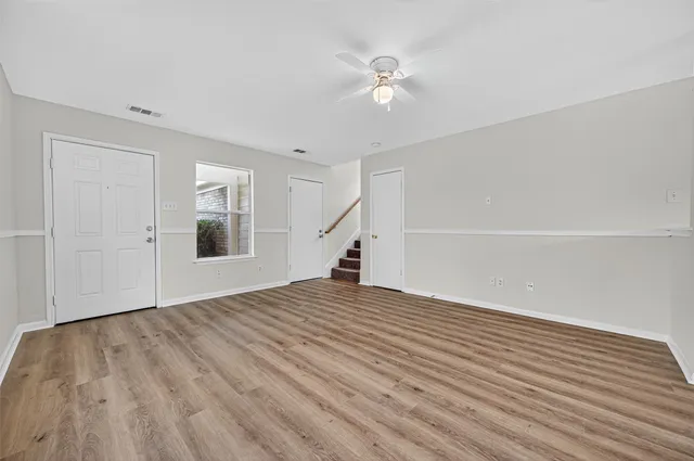 a view of an empty room with wooden floor and a window