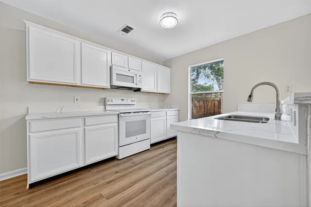 a kitchen with white cabinets and white appliances